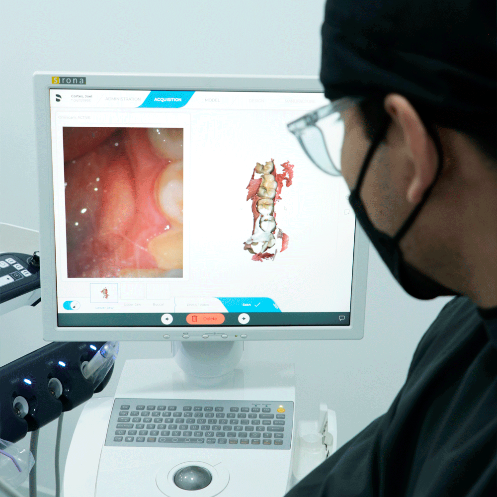 A dentist examining a 3D dental software interface, with a simultaneous view inside a patient's mouth, highlighting advanced dental technology