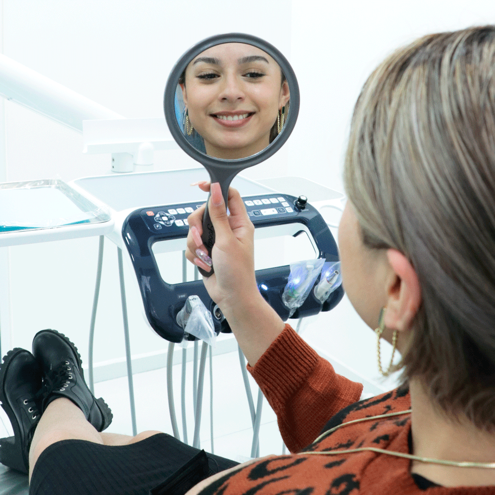 A satisfied patient holding a mirror, gazing at their radiant smile transformed by a dental treatment